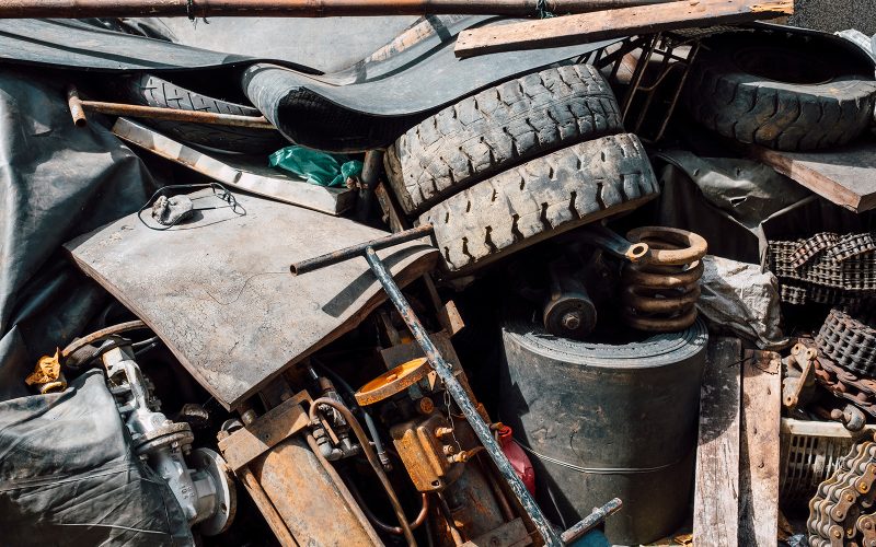 Pile of assorted waste management materials, including tires, metal parts, and mechanical equipment.