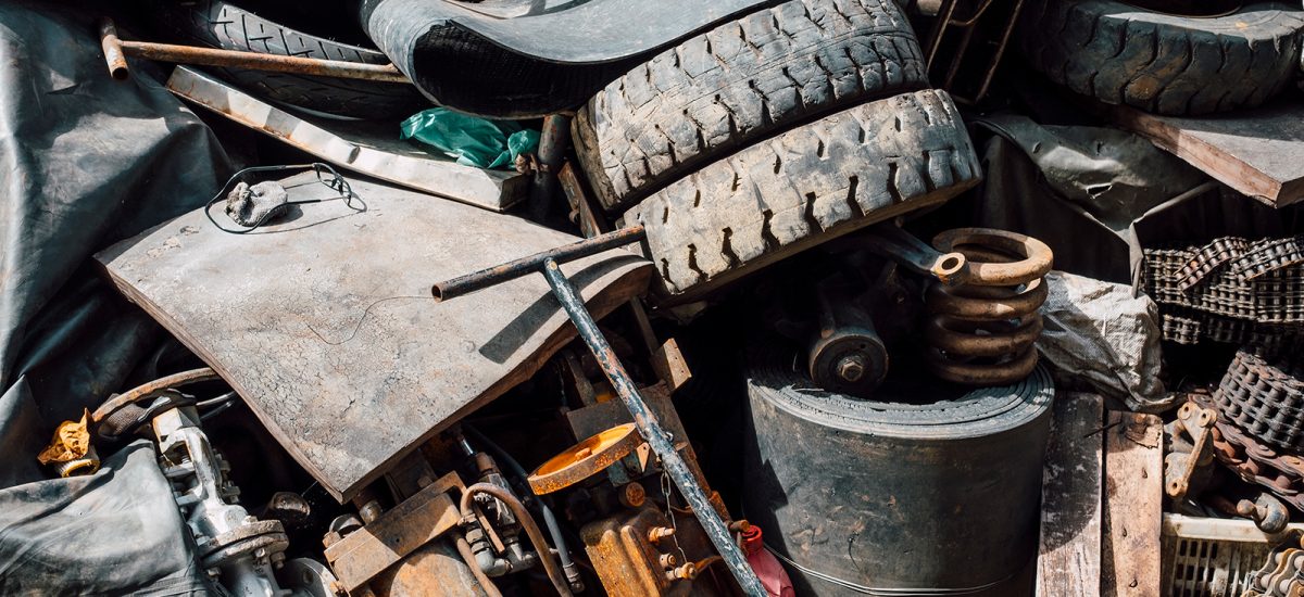 Pile of assorted waste management materials, including tires, metal parts, and mechanical equipment.